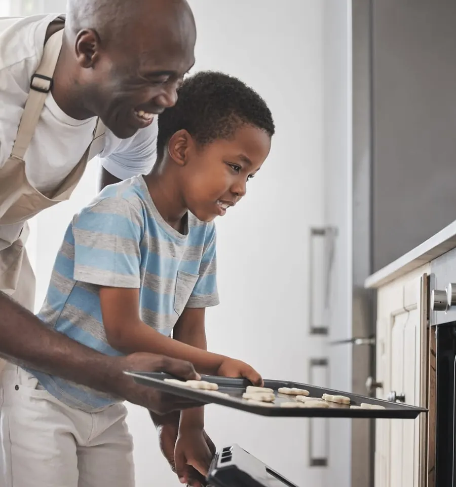 A father and son baking together at the oven