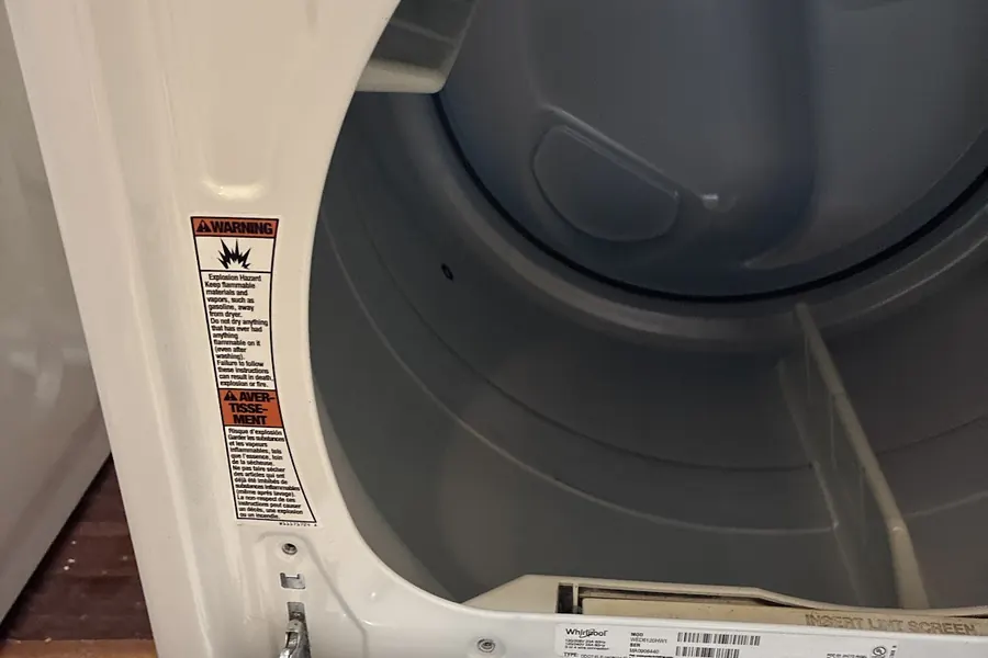 A dryer with its door open, photographed by Plaza Appliance Service Co