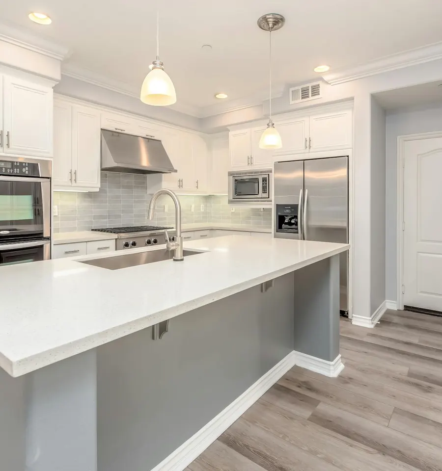 A bright kitchen with an island, a stainless refrigerator, and a range
