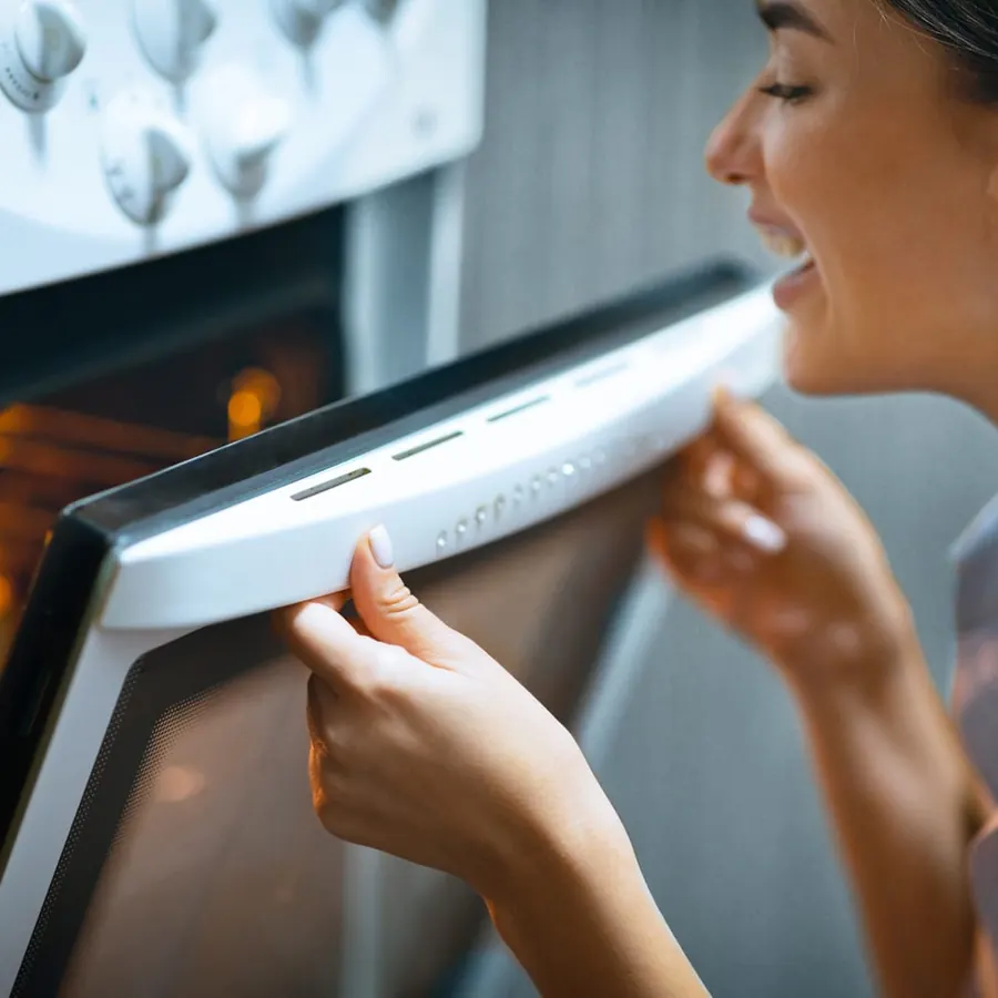A homeowner opening a wall oven to check on baking