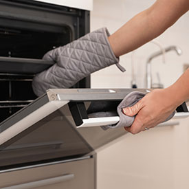 bigstock-Woman-Putting-Baking-Tray-Into-268106860_275